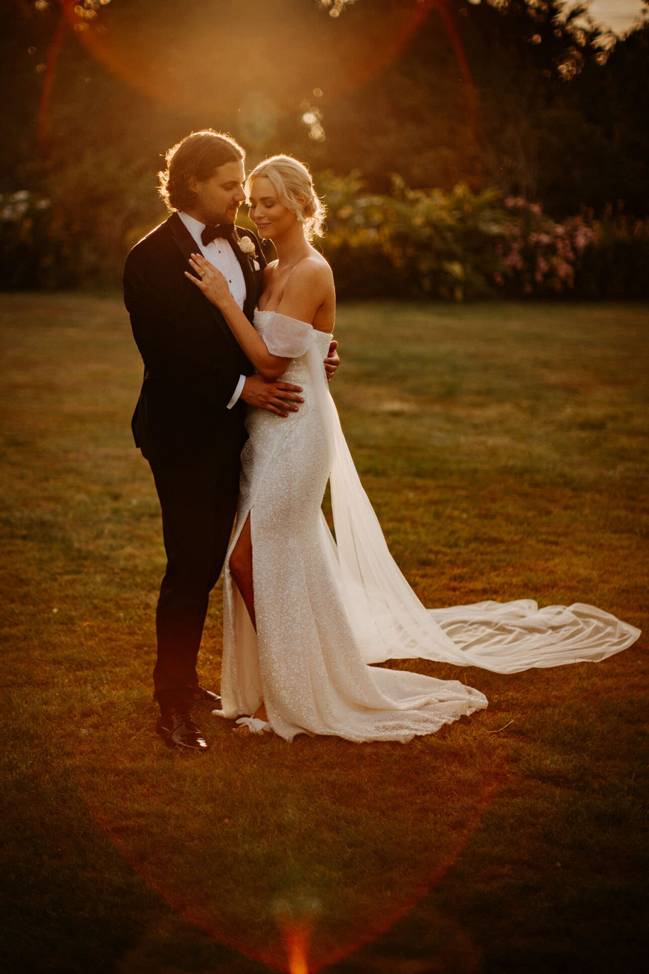 A bride and groom captured in the golden hour sun, embracing in the gardens at high house